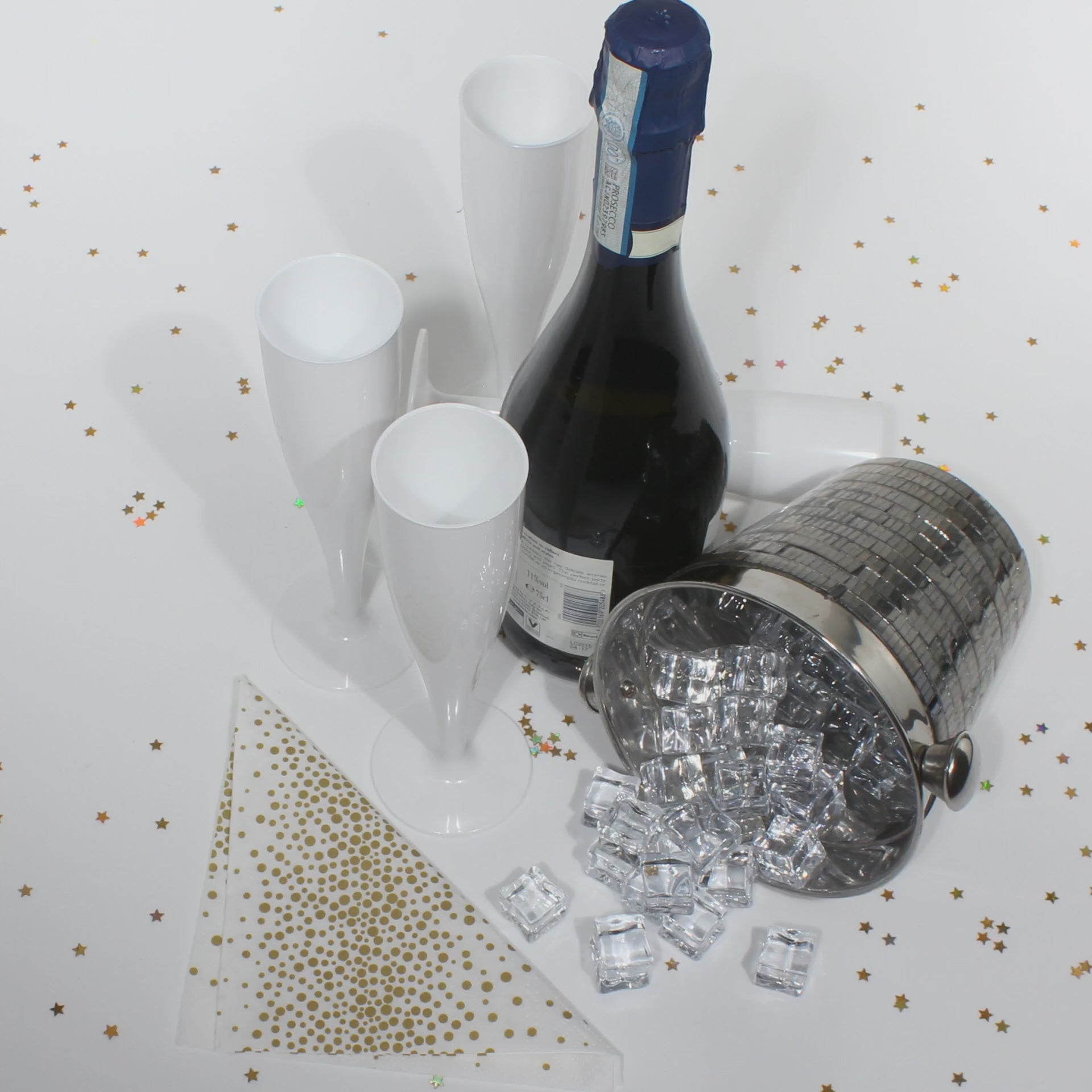 A video of several white champagne flutes with a bottle of prosecco, an ice bucket with ice cubes and gold glitter on the table